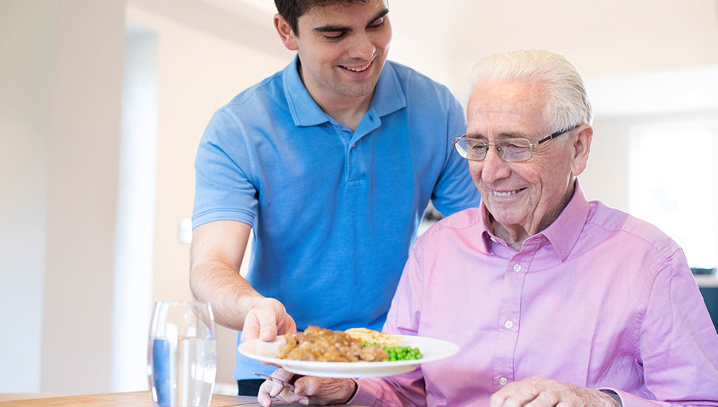 man serving dinner to an elderly man